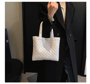Dettaglio di borsa tote trapuntata bianca con finitura lucida e ricamo di lusso