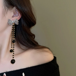 Leopard print bow long tassel earrings on model featuring black beads and gold-tone metal