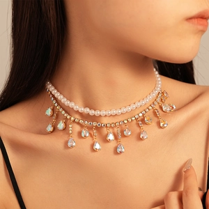 Detail view of a double-layer necklace with white pearls and a golden teardrop gemstone