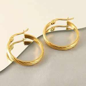 Macro detail of gold round hoop earrings with elegant twisted texture and pin closure
