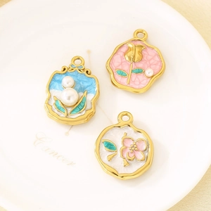 Détail de pendentifs floraux émaillés français vintage avec perles sur plat céramique
