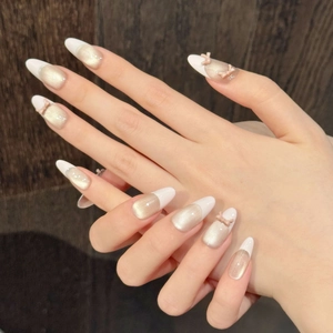 Detail of almond-shaped press-on nails with French tips and 3D pink bow accents