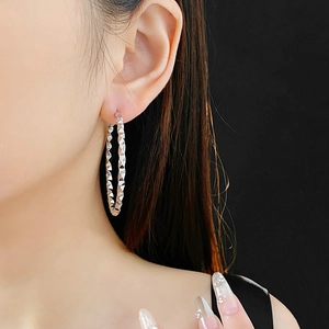 Macro shot of silver irregular geometric textured hoop earring on a model with black background