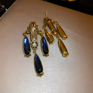 Detail of vintage Baroque earrings with blue water-drop stones and gold metal finish