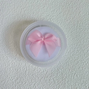 Detail of white crystal velvet powder puff with pink ribbon bow in transparent case