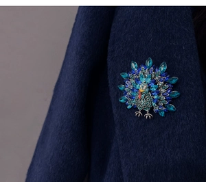 Detail of peacock brooch with blue rhinestones pinned on a dark navy wool coat fabric