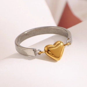 Dettaglio dell'anello a cuore bicolore con pendente dorato e fascia d'argento su bianco