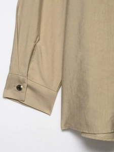 Detailed close-up of khaki woven fabric with a signature gold metal button fastener
