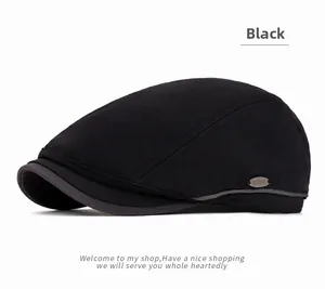 Detail of black herringbone flat cap featuring a side metal logo and textured fabric
