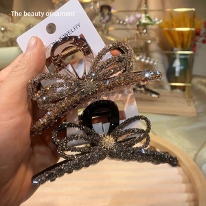 Detailed view of large champagne gold and dark grey rhinestone bow hair claw clips
