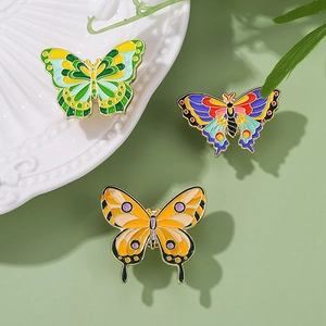 Three colorful alloy butterfly brooches with enamel finish on a light green background
