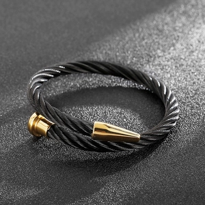 Macro detail of men's black twisted cable bracelet with elegant gold cone-shaped ends