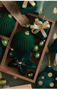 Detail of dark green velvet Christmas ornaments in diverse shapes on a rustic wooden tray