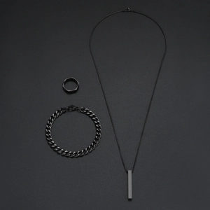 Parure bijoux noire minimaliste avec collier barre, bracelet gourmette et bague géométrique