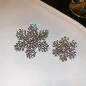 Close-up of sparkling snowflake hair clips with micro-pave crystals on a white tray
