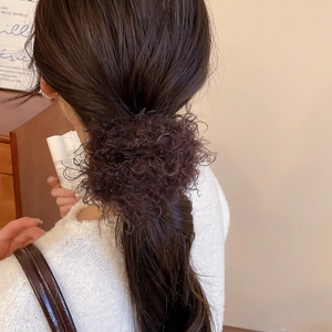 Close-up of curly faux fur hair scrunchie in dark brown with soft fluffy texture