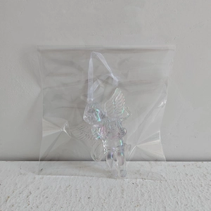Detailed view of a clear iridescent acrylic angel ornament with white string packaging