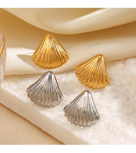 Detailed view of silver and gold shell earrings set on white stone with satin fabric