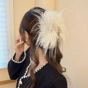 Détail de la grande pince à cheveux en plumes blanches portée sur l'arrière de la tête