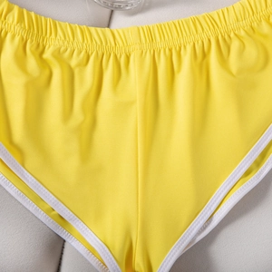 Detailaufnahme der gelben Sporthose mit weißer Paspelierung und elastischem Bund