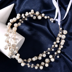 Detailed close-up of handmade bridal headband with white petals and pearls on blue silk