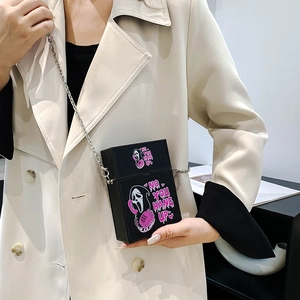 Black Ghostface crossbody bag with silver chain strap worn over a beige trench coat