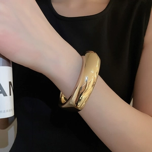 Gros plan d'un bracelet jonc doré épais minimaliste avec une finition miroir polie