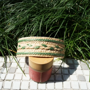 Detail of beige raffia headband with green woven stripes on a decorative glass jar