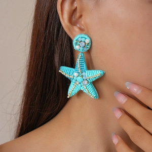 Close-up of model wearing starfish earrings with blue beads and crystals for beach style