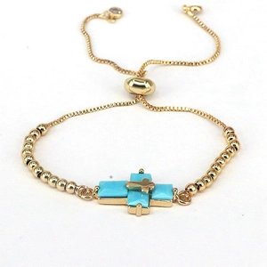 Detailed macro view of gold-plated box chain bracelet with blue zircon cross charm