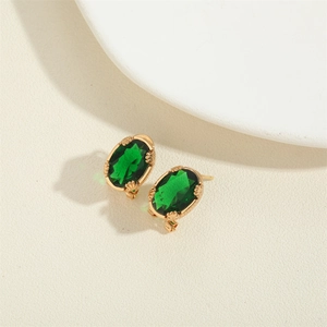 Vintage gold earrings featuring oval green crystal stones on a textured surface
