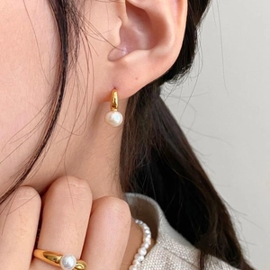 Close-up of elegant gold pearl drop earrings and matching ring on model for a chic style
