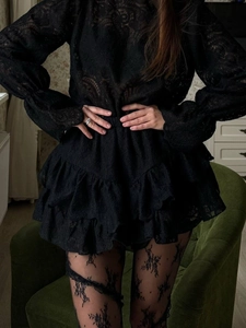 Detail of black lantern sleeve lace top paired with layered ruffle skirt and floral stockings