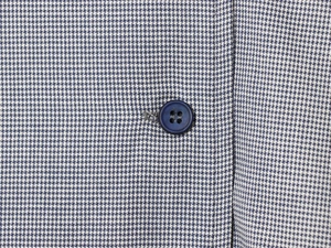 Close-up of blue and white plaid fabric texture with a navy four-hole round button detail