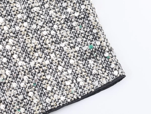 Close-up of black and white tweed fabric with shimmering silver sequins on sleeveless dress