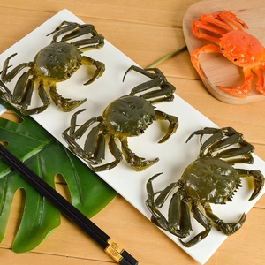 Realistic PVC crab models in green and red displayed on a white tray with wooden background