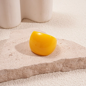 Close-up of a bright yellow chunky resin ring on a textured stone aesthetic tray
