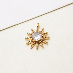 Macro detail of sunburst jewelry pendant in gold finish with central zircon inlay