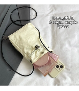 Detail view of cream drawstring bucket bag showing interior space for phone and makeup