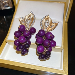 Gros plan de boucles d'oreilles raisin violettes étincelantes dans un coffret cadeau
