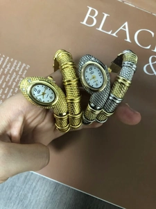 Detail of snake-shaped wrap bracelet watch in gold and silver finishes with quartz dial