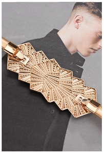Détail d'une ceinture élastique dorée avec boucle géométrique gravée motif soleil