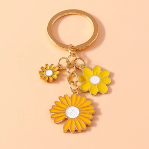 Detail shot of metal keychain featuring yellow and white enamel daisy floral pendants