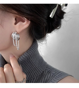 Close-up of layered silver chain earrings with tassels and sparkling cubic zirconia stones