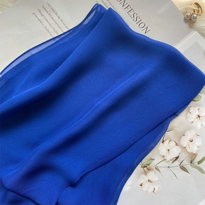 Detail of royal blue mulberry silk scarf with fine texture, styled with pearl accessories