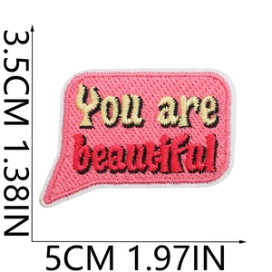 Detail of pink embroidered patch featuring You are beautiful text and size measurements