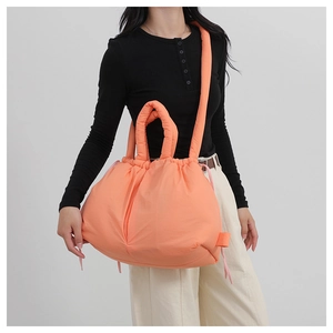 Lifestyle shot of an orange padded nylon tote bag with drawstring and quilted handle
