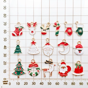 Detailed view of 15 festive Christmas enamel charms with ruler scale for size reference