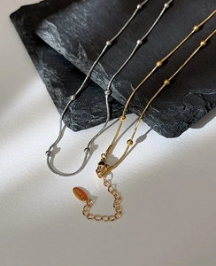 Dettaglio macro di collane a maglia serpente oro e argento su pietra scura