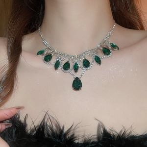 Detail of luxury necklace featuring green teardrop crystals in silver claw settings